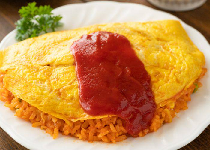 Japanese omurice: a mix of rice, meat and vegetables covered in a bright yellow omelet and smothered in ketchup.